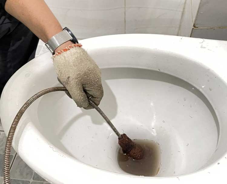 Dùng dây hoặc lò xo thông bồn cầu